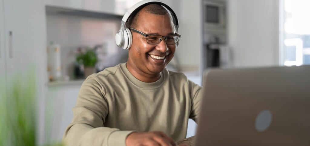 A happy older man takes a video call on his laptop