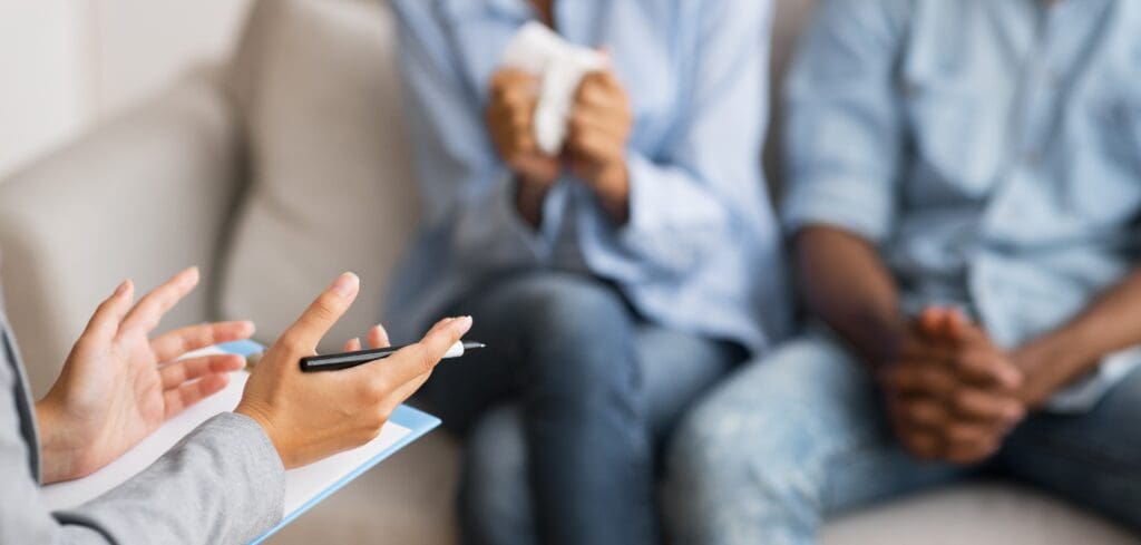 Image of the hands of a therapist as she sits in front of her clients